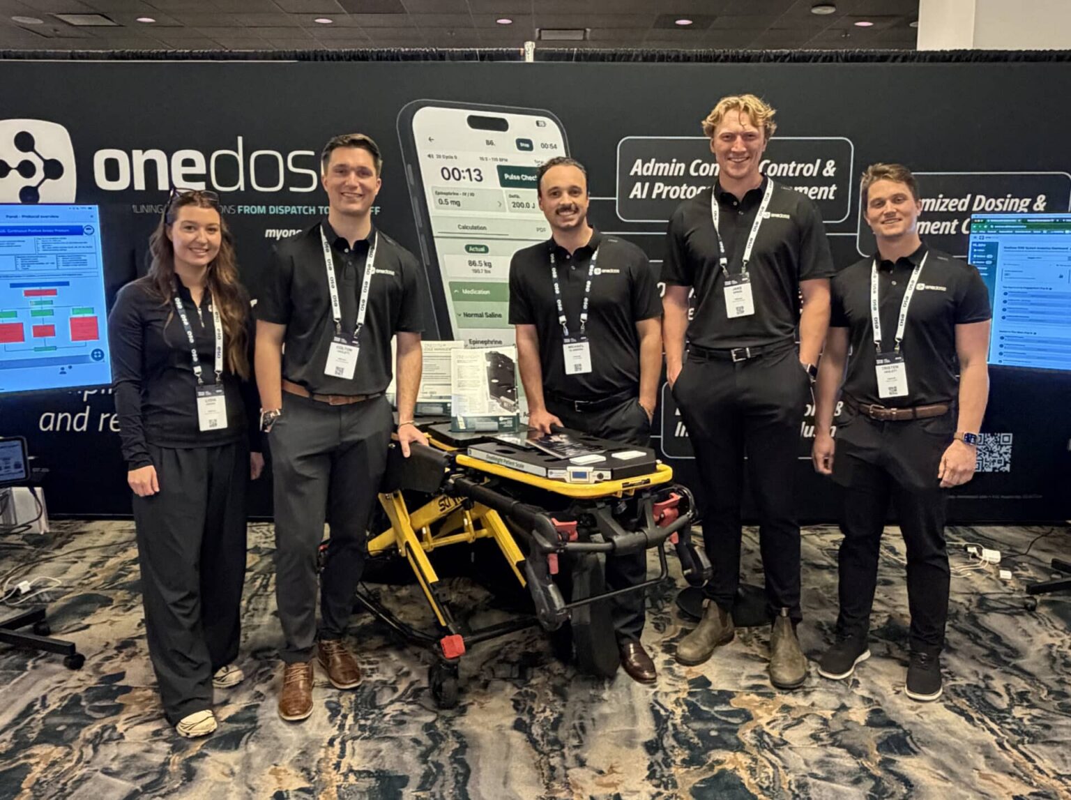 The OneDose team at a trade show booth with a OneWeight cot