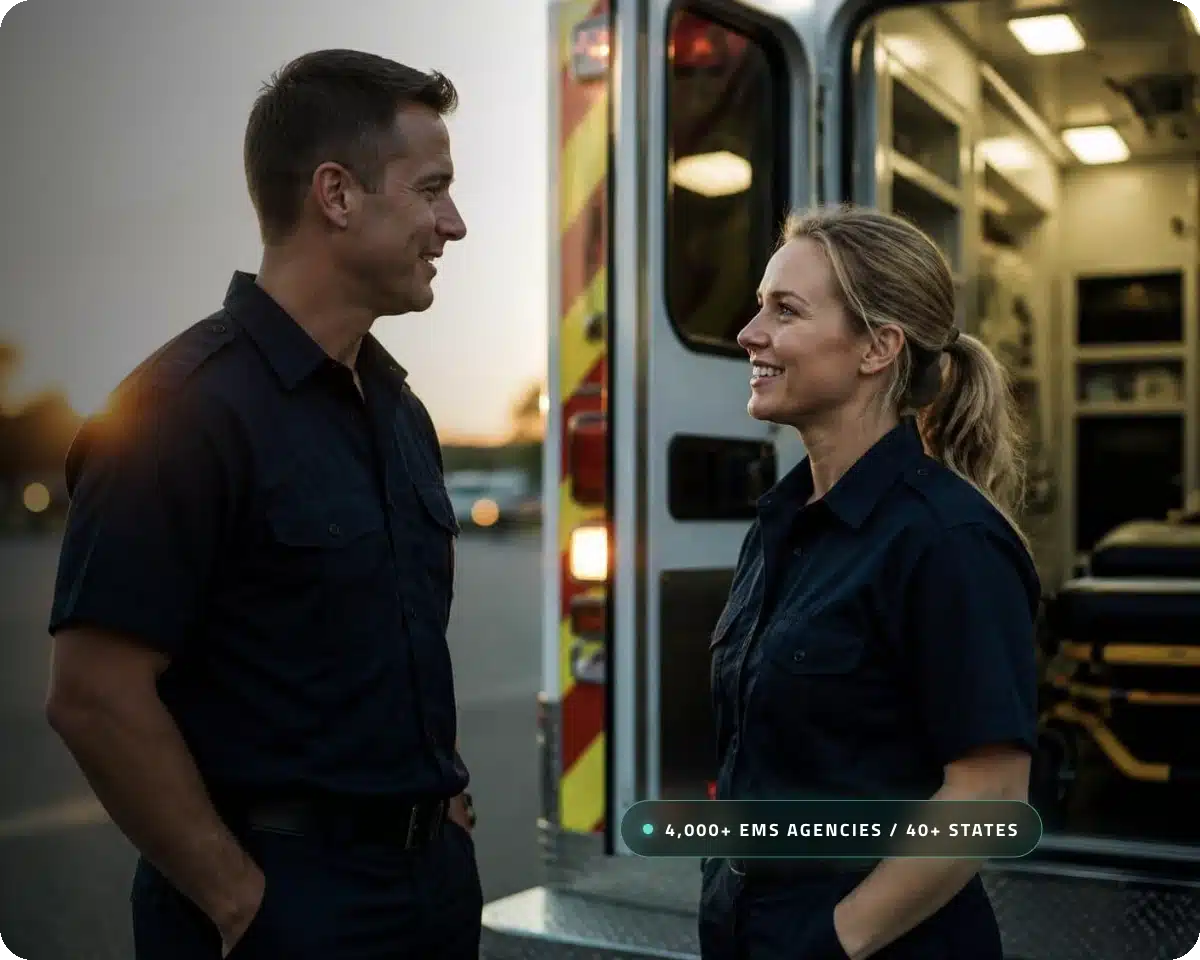 Two paramedics talking beside an ambulance at sunset